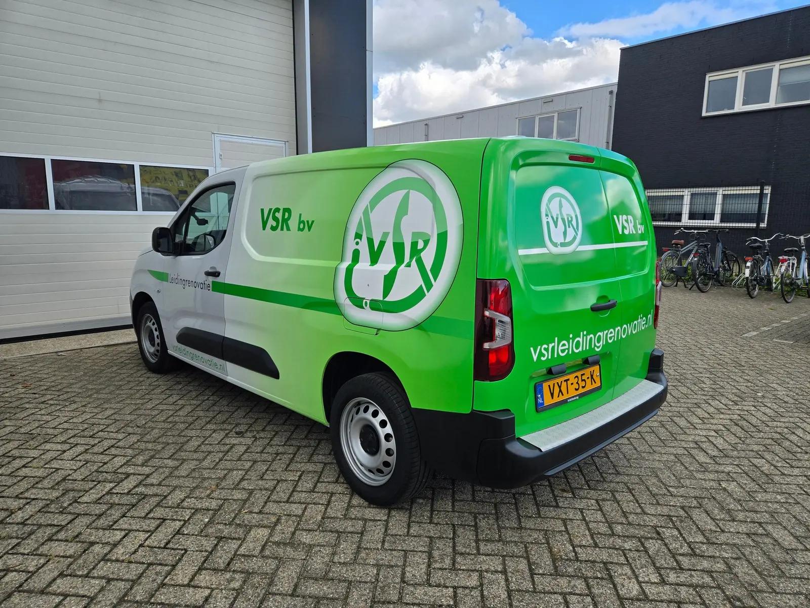 VSR-bedrijfswagen van schuin achteren met groene achterzijde en witte logo’s.