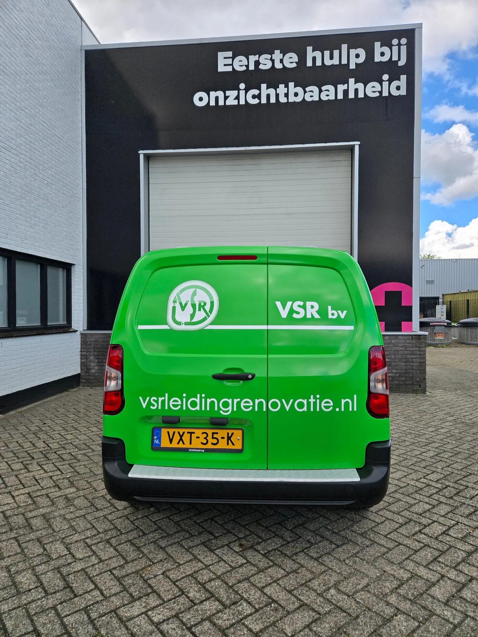 Achterzijde van de VSR Peugeot Partner met wit logo, bedrijfsnaam en website op groen.