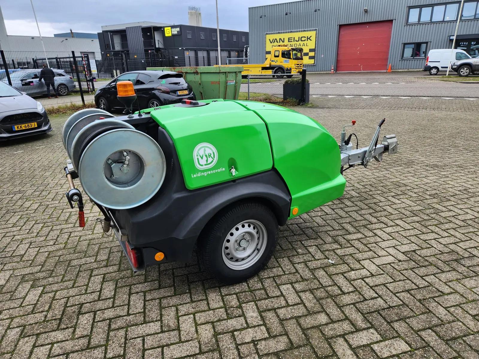 VSR-aanhanger van opzij met groene behuizing en witte belettering naast de slangenrollen.