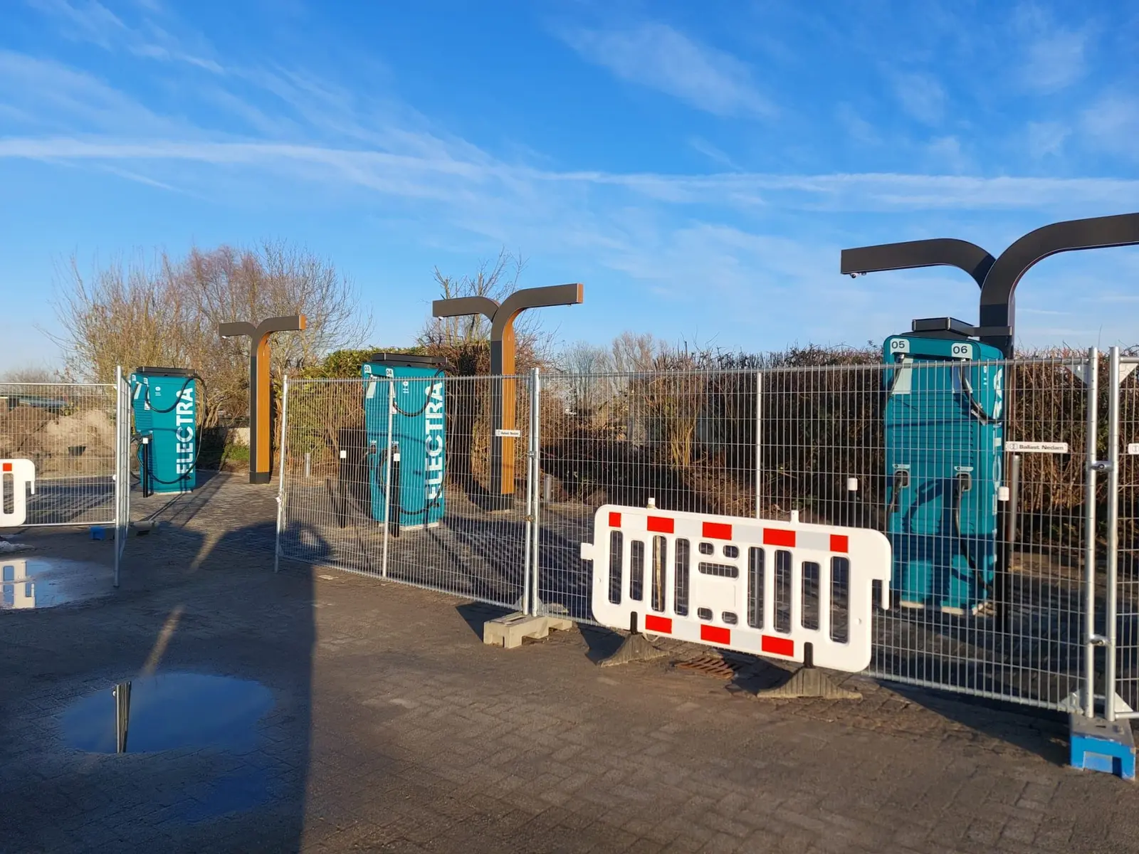 Meerdere turquoise Electra-laadstations met witte belettering tijdens de inrichting van een laadlocatie.