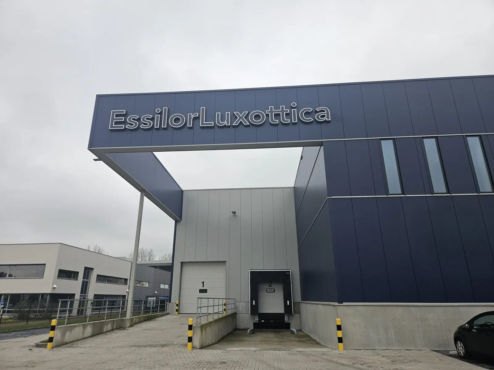EssilorLuxottica-gevelletters boven de entree in Wijchen, overdag gefotografeerd.