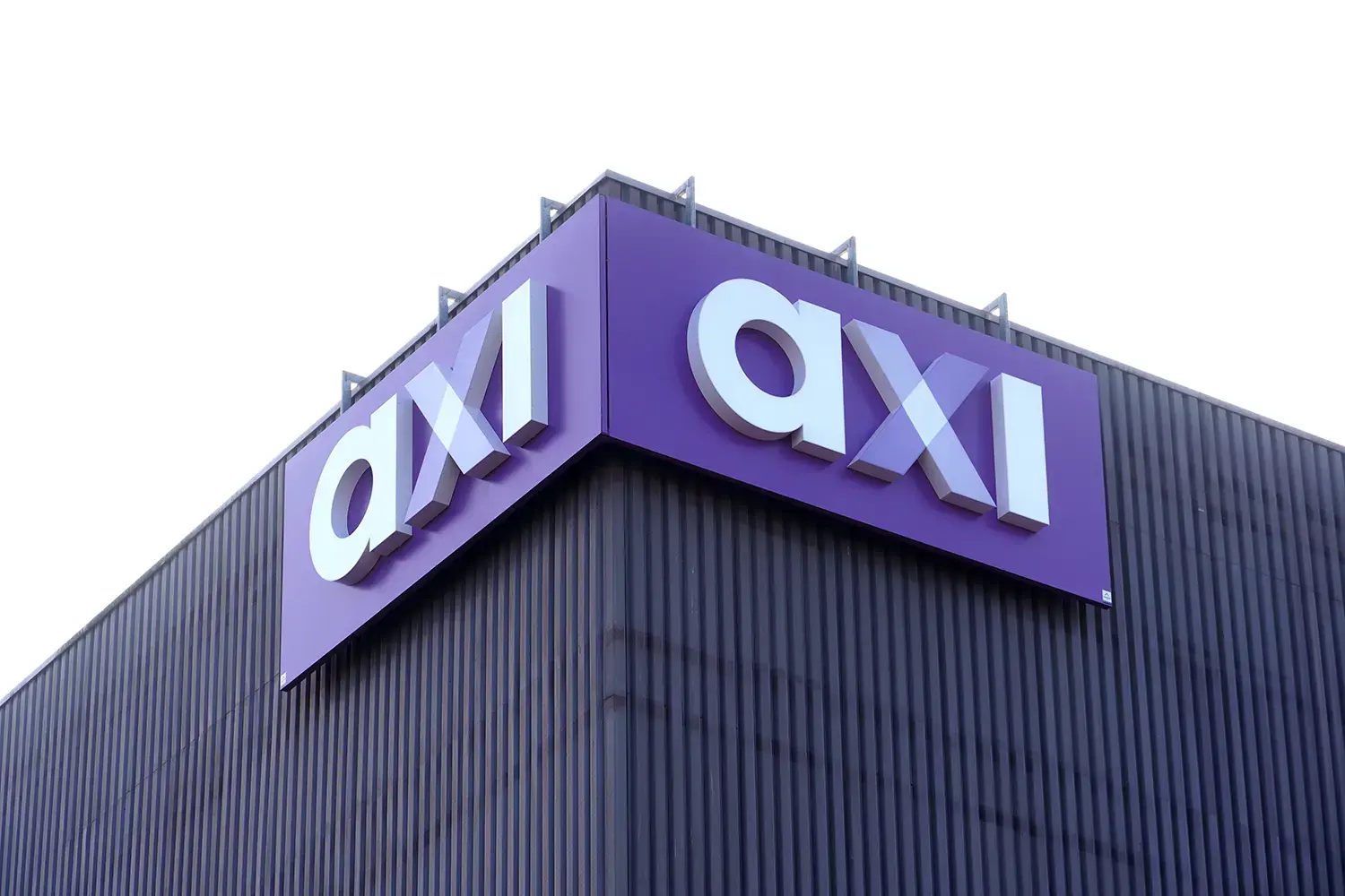 Paarse hoekgevelreclame met witte 3D doosletters "axi" gemonteerd op de donkere metalen gevel van een modern bedrijfspand.