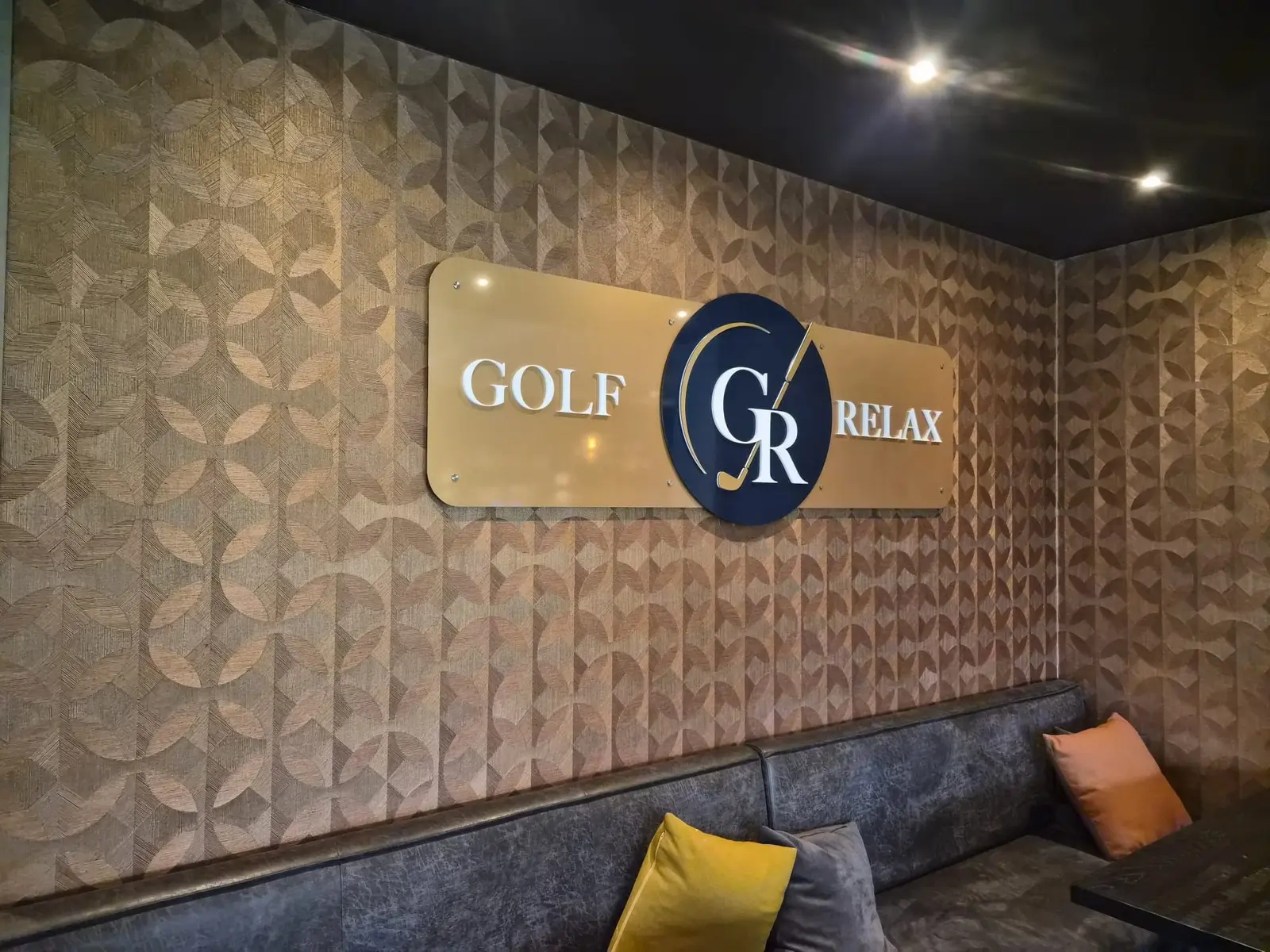 Golf & Relax-interieurlogo op goudkleurige panelen boven een zitbank.