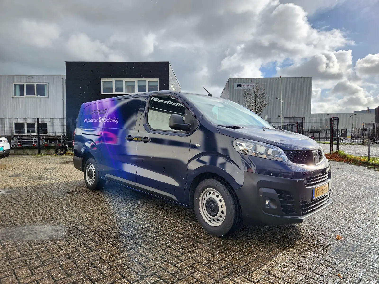 Paars-blauwe Luminaid-buswrap op een Fiat Scudo, van schuin voor gezien.
