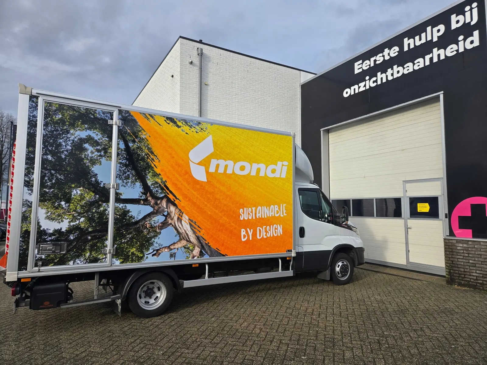 Side of the Mondi box van with an orange brand panel, white logo and large photographic graphics.