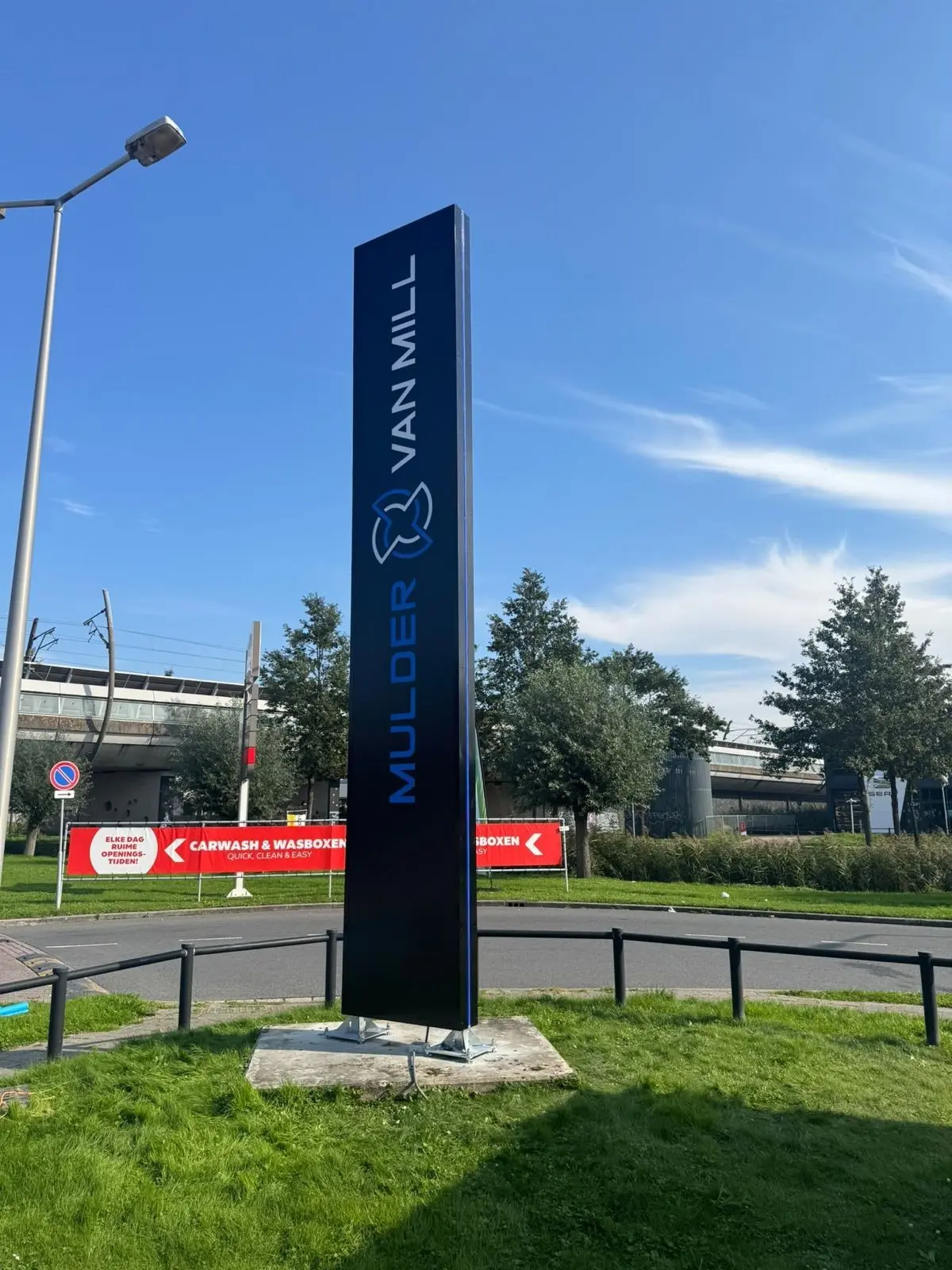 Dark Mulder van Mill signage pylon with blue and white lettering beside the Rotterdam site.