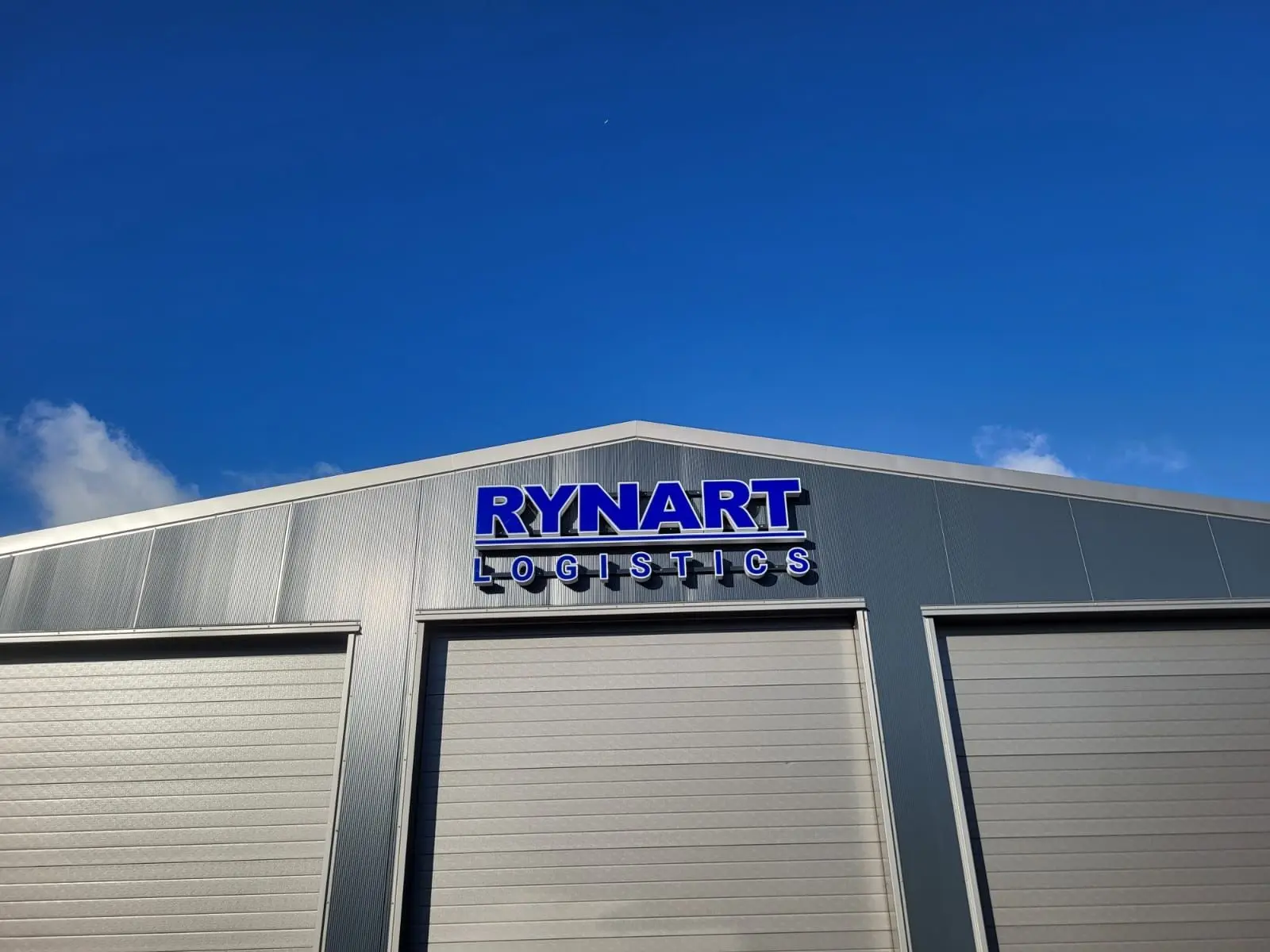 Blauw-witte Rynart Logistics-gevelletters boven de middelste loodsdeur.